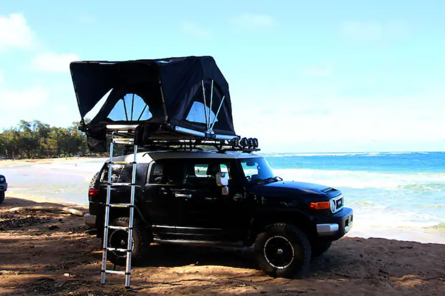 Explore with this RV rental: A Toyota FJ Cruiser with a rooftop tent ready for beach camping.