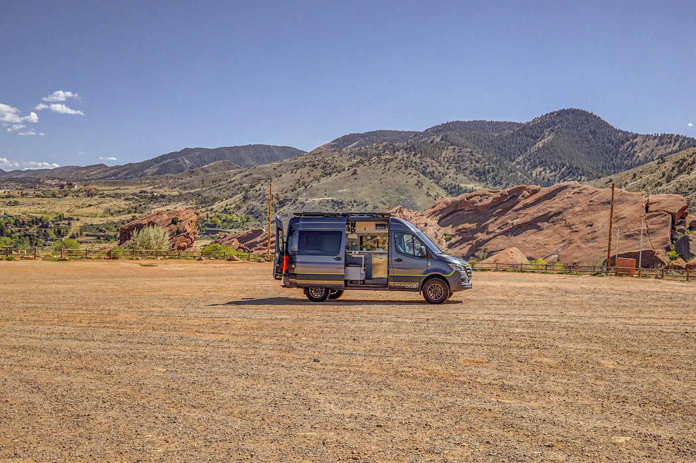 Explore the outdoors in this customized dark grey camper van, perfect for your next RV rental adventure amidst mountains & red rocks.
