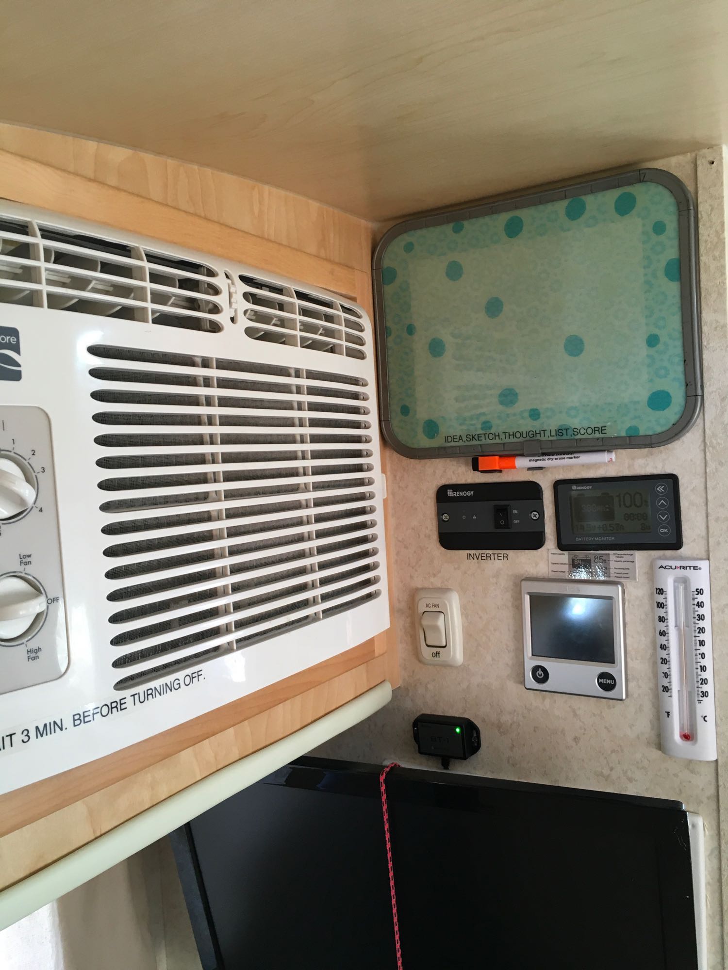 RV rental interior wall showing an AC unit, Renogy power/battery monitors, and climate controls like a thermostat and thermometer.
