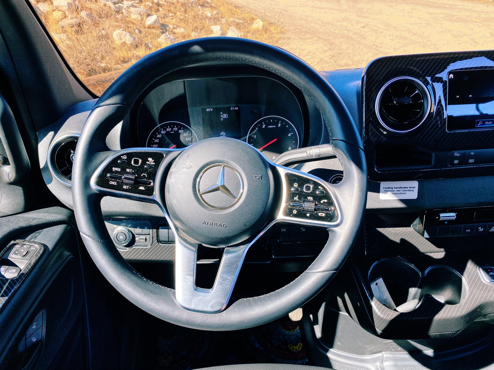 Interior of a Mercedes-Benz RV rental, showing the modern dashboard, steering wheel, and climate controls on a sunny day.
