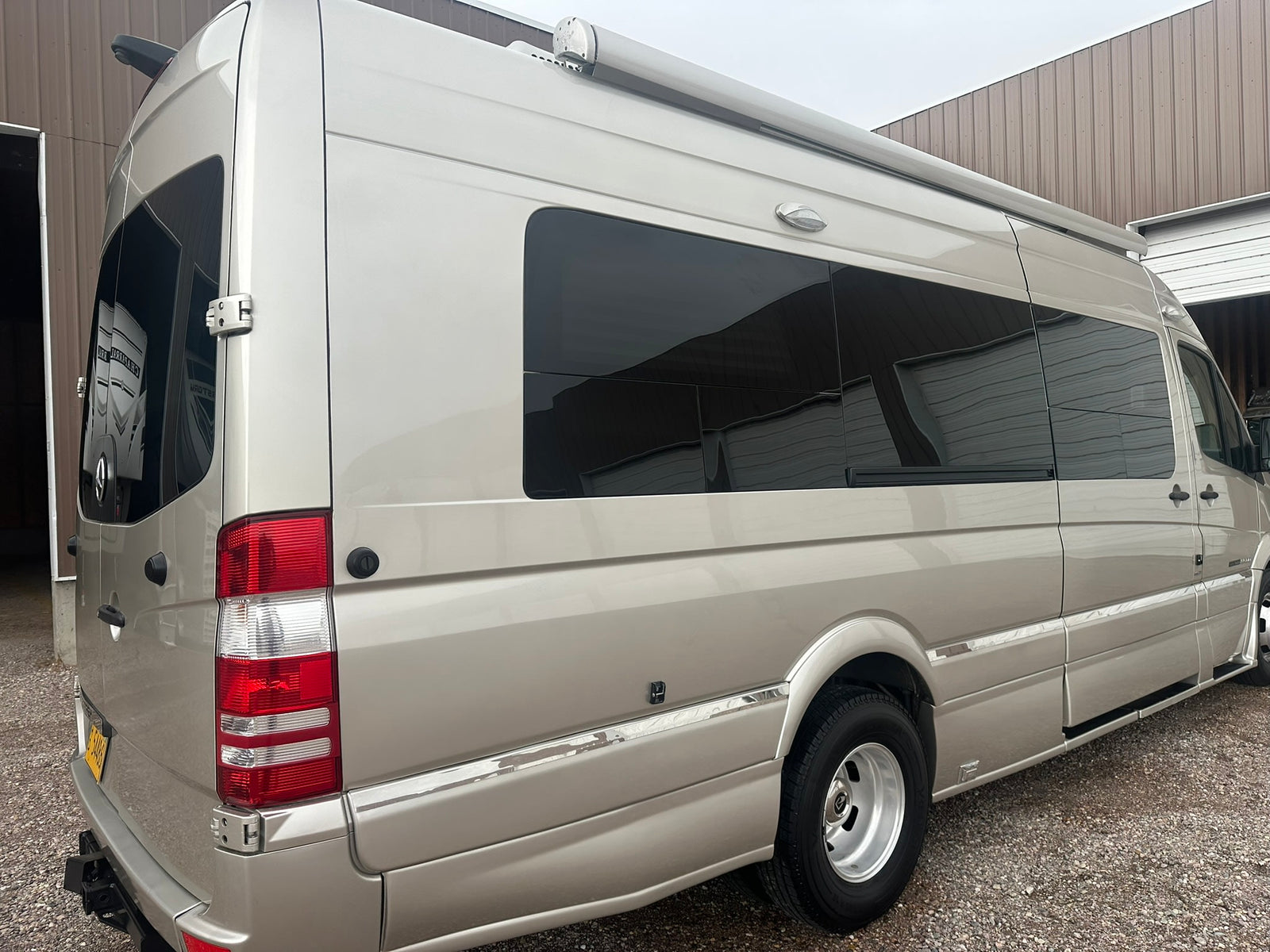 lined up outdoors near a building with a red roof.|This Roadtrek Mercedes-Benz Sprinter camper van