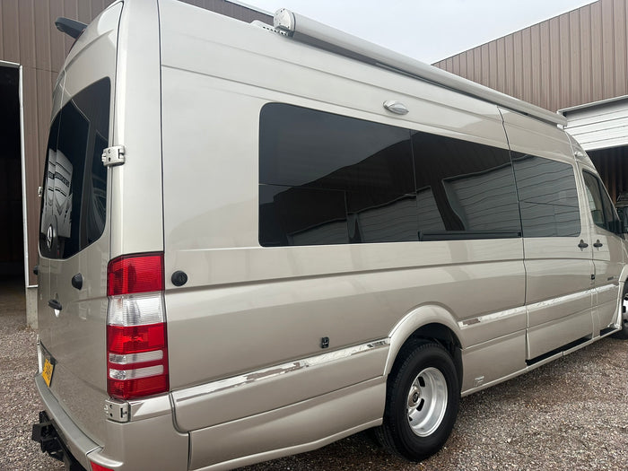 lined up outdoors near a building with a red roof.|This Roadtrek Mercedes-Benz Sprinter camper van
