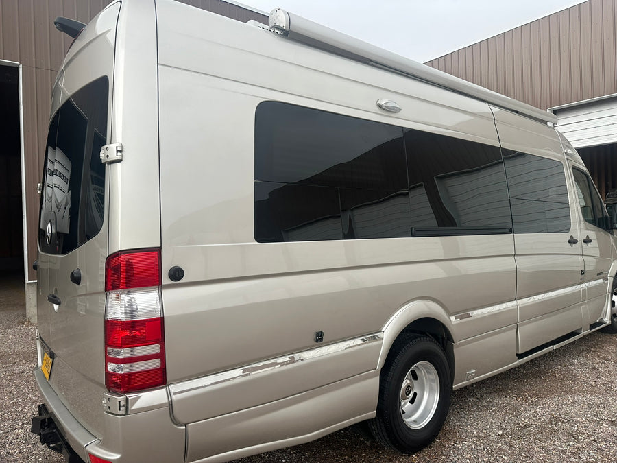 lined up outdoors near a building with a red roof.|This Roadtrek Mercedes-Benz Sprinter camper van