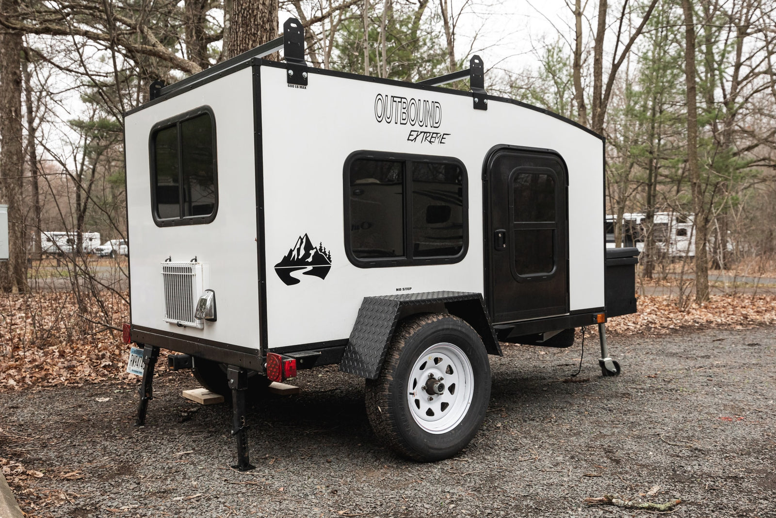 An Outbound Extreme compact travel trailer, ideal for RV rental and outdoor adventures in a wooded campground.