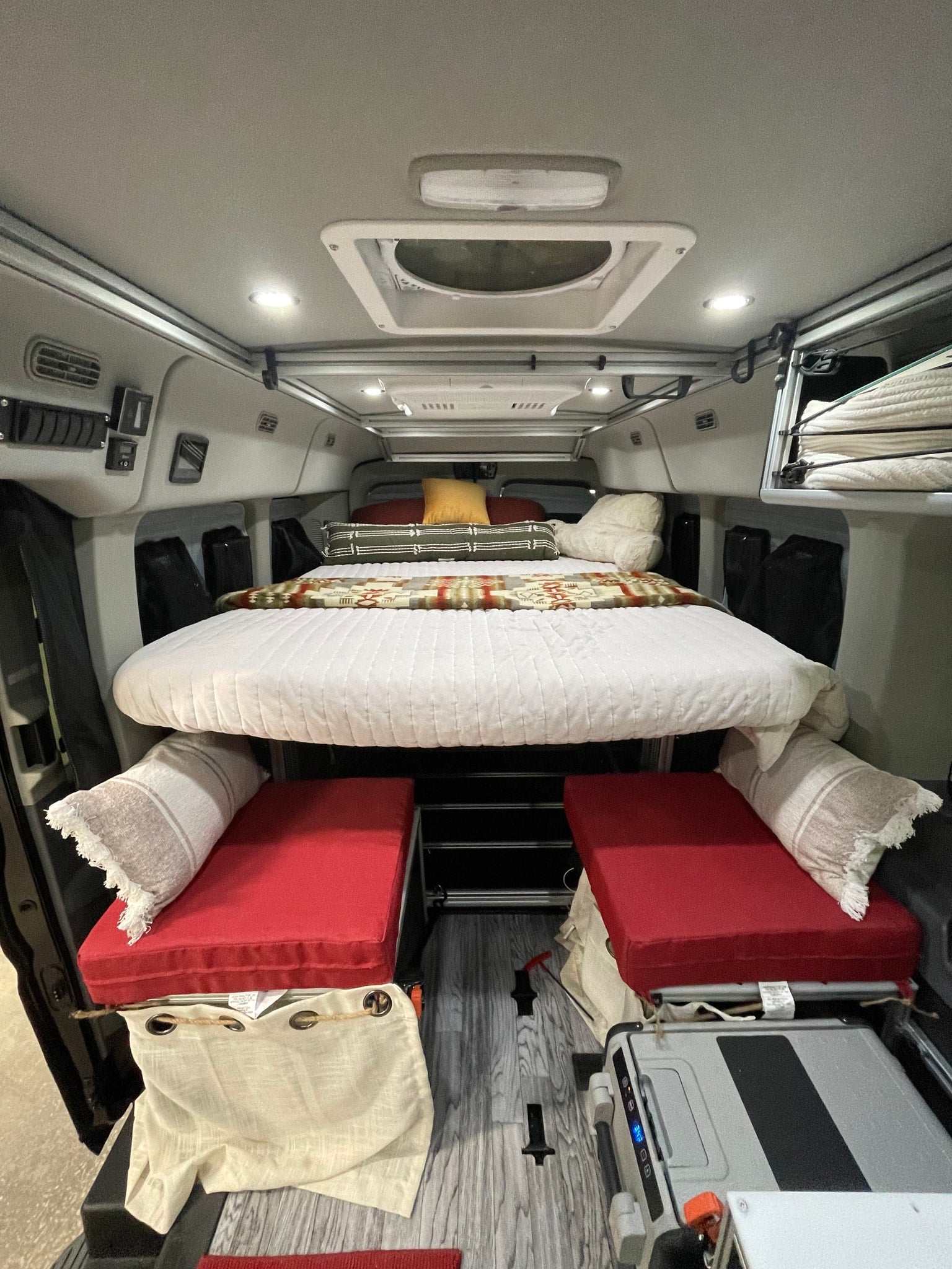 Inside an RV rental: a clever, elevated bed over red bench seating, perfect for adventurous road trips.