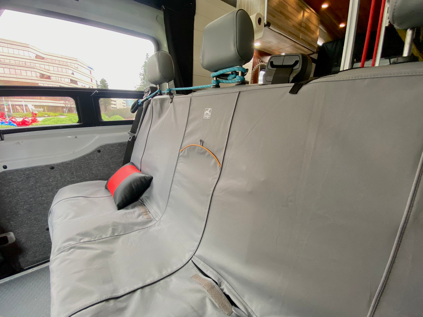 Inside an RV rental: A grey seat cover protects the rear bench, secured by rope around headrests. Ready for travel.