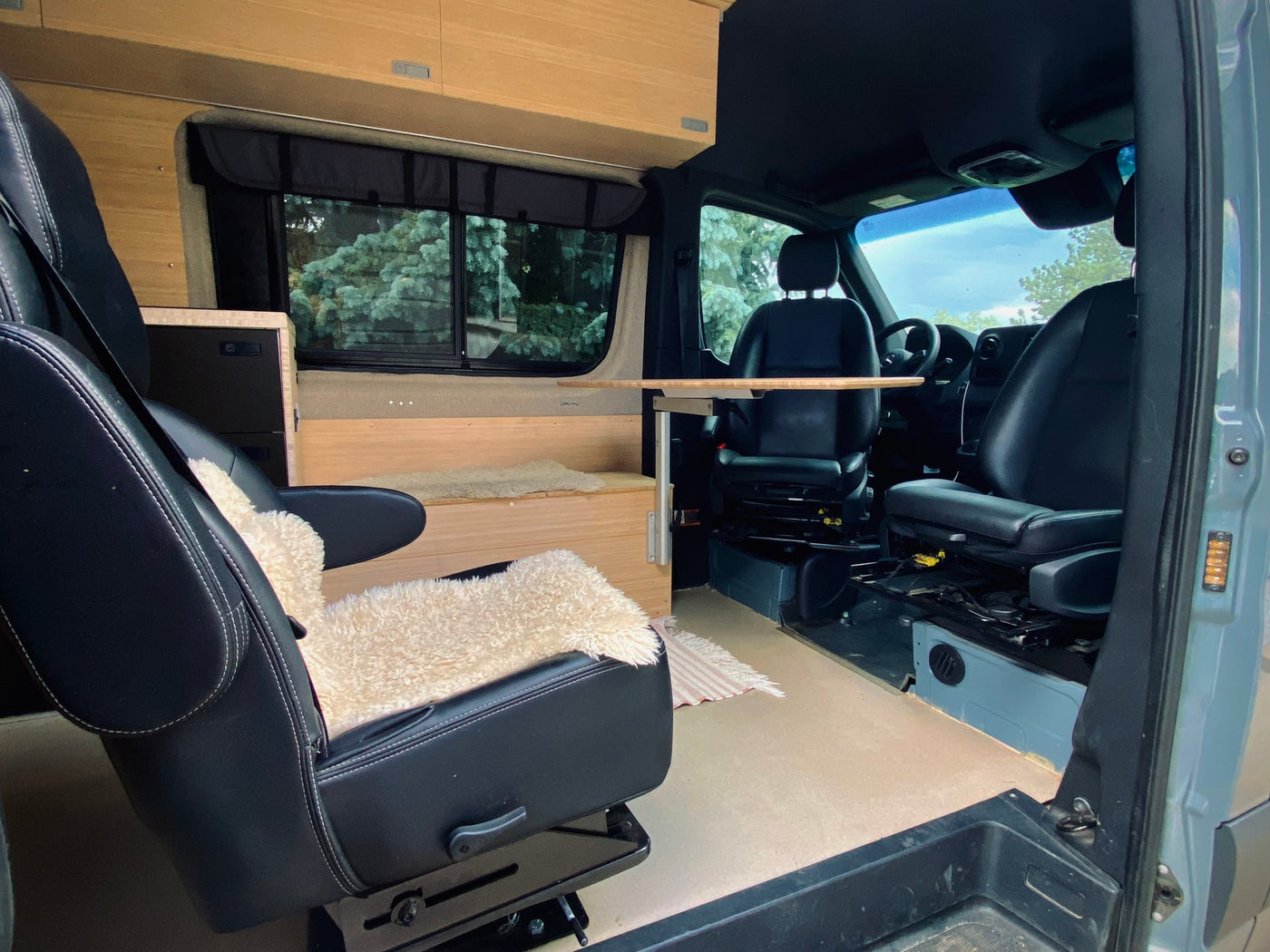 and a view outside.|RV rental interior: a compact camper van with wooden walls — photo 4