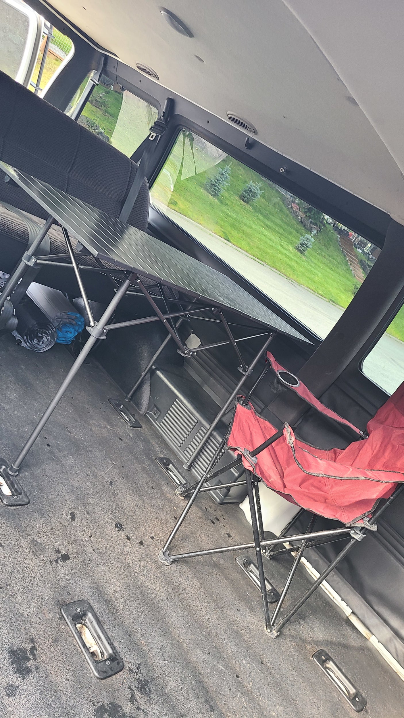 Interior view of an RV rental: A portable folding table and red chair are set up inside, ready for comfortable travel.