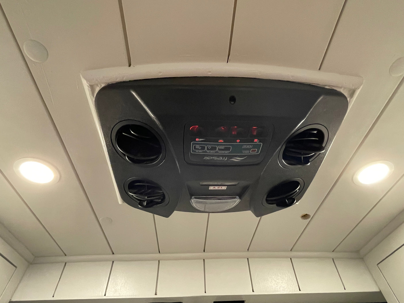 Modern RV rental ceiling showing a black Fresair cooling unit with air vents, control panel, and recessed LED lights.