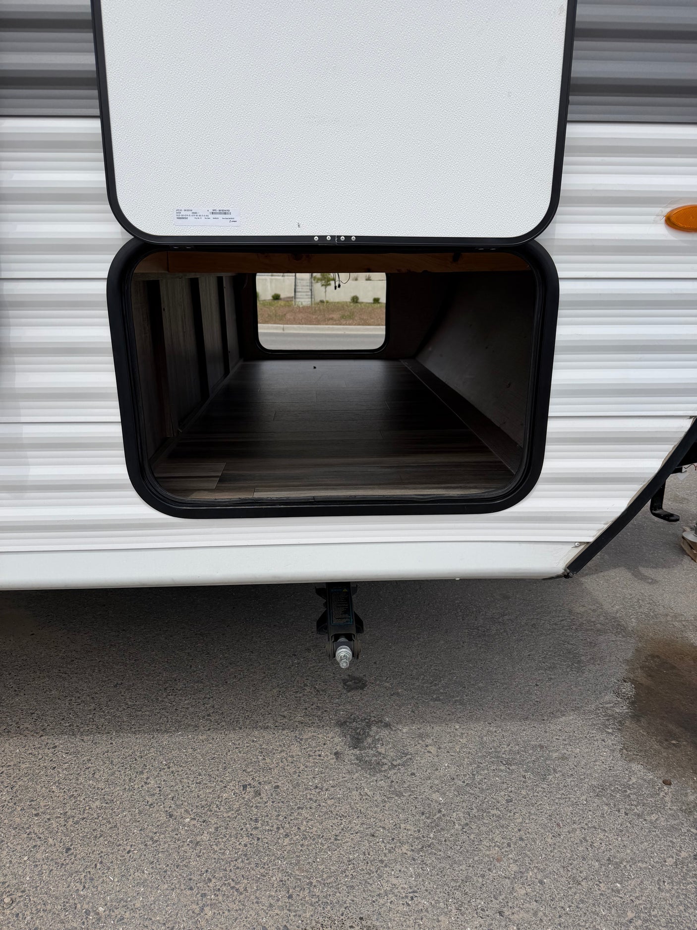 Open pass-through storage on an RV rental, ideal for packing gear. A stabilizer jack is visible below the compartment.