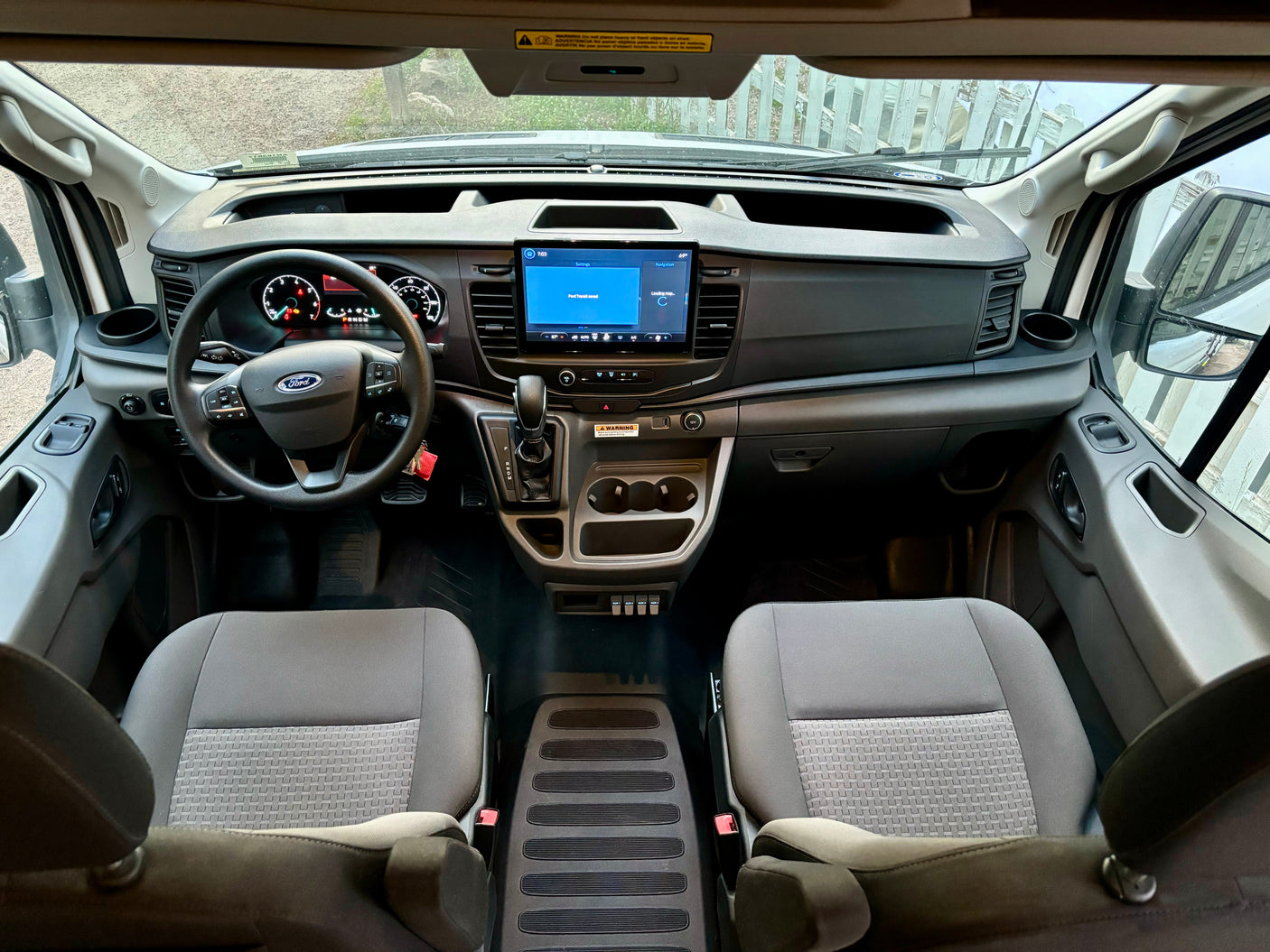 Inside a Ford Transit rv rental, showing the spacious driver's area, dashboard, and infotainment system.