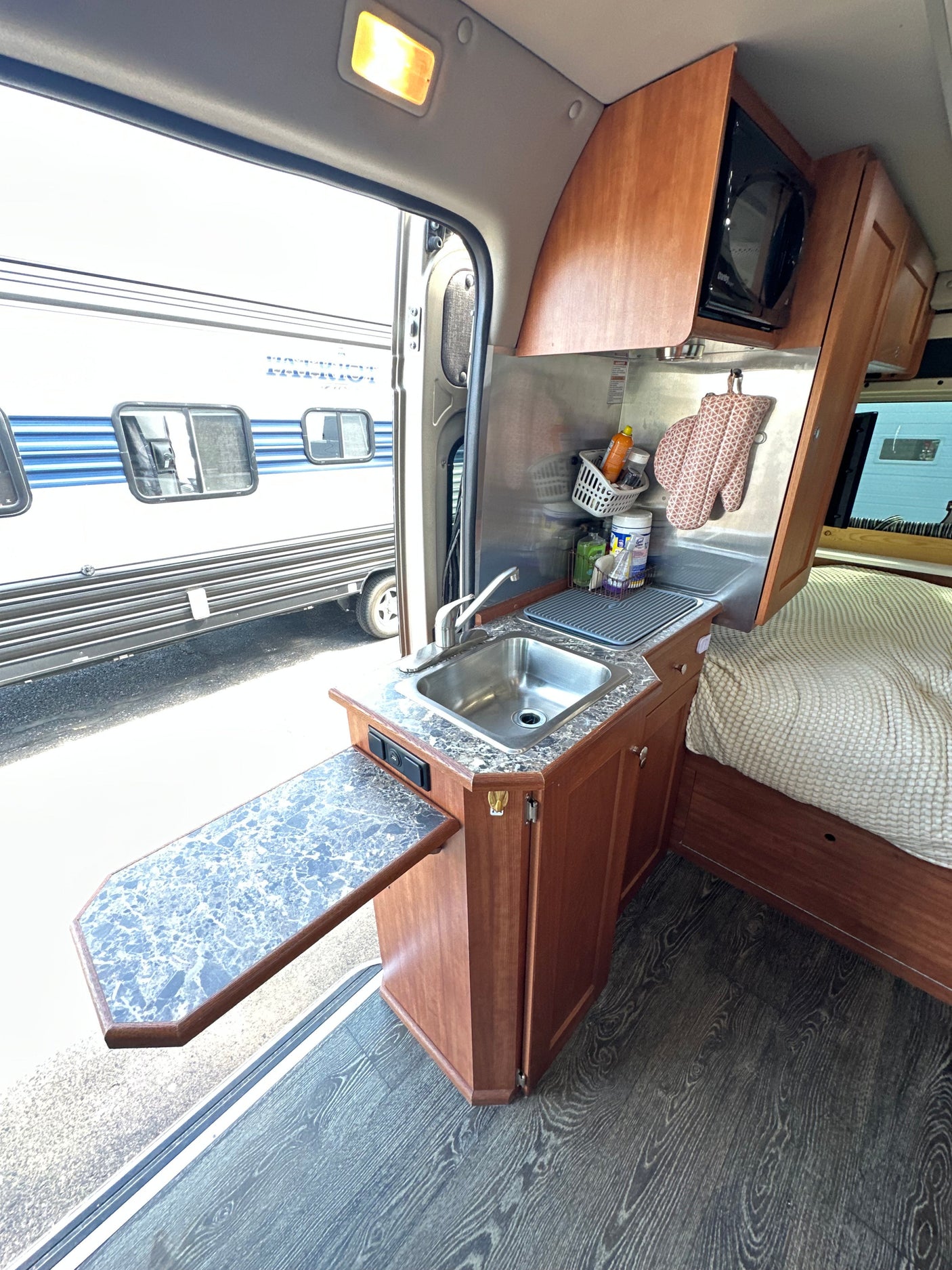 Inside this RV rental: kitchen with sink, microwave, and expandable counter. Adjacent cozy sleeping area for comfort.