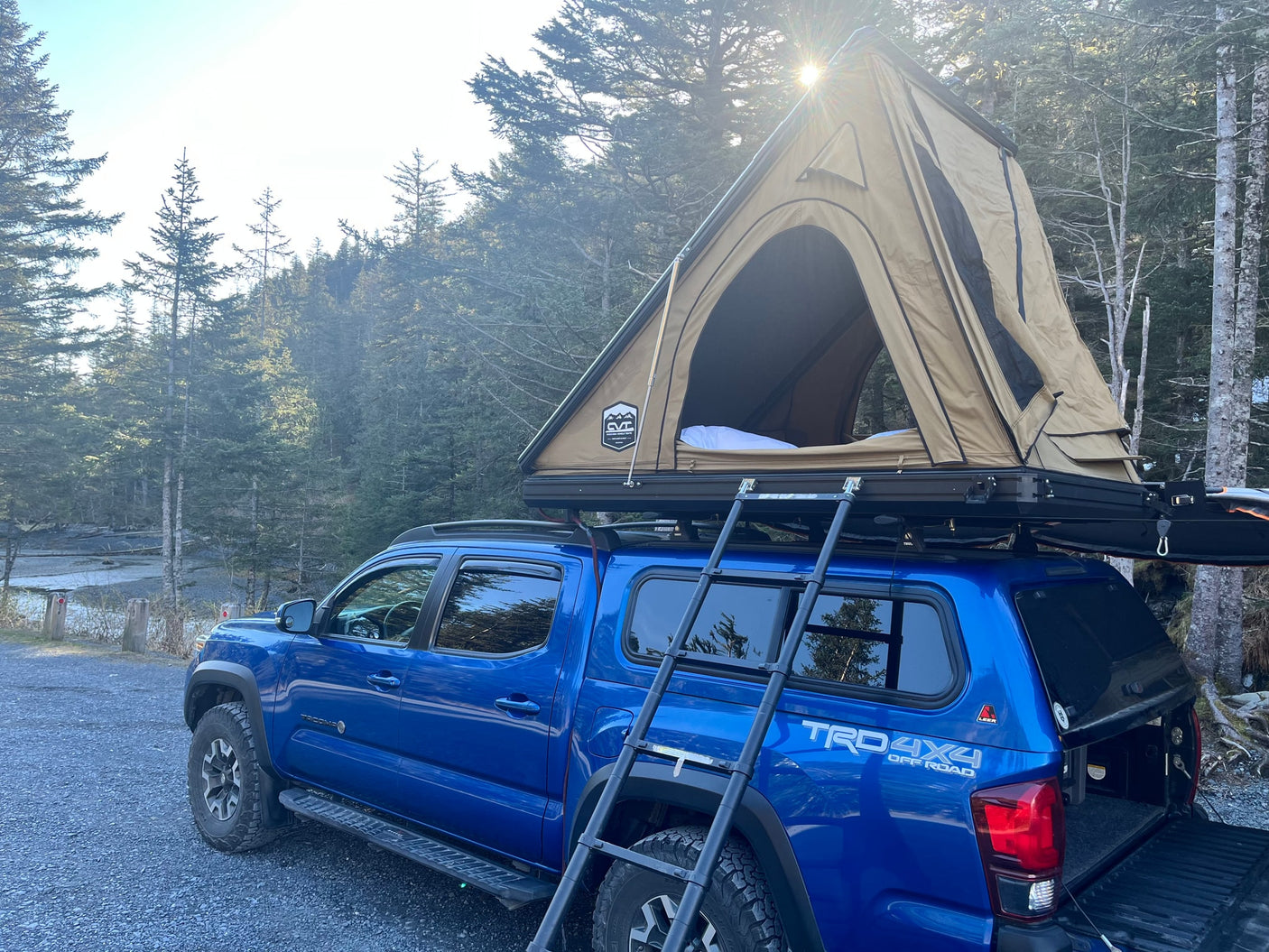 This blue Toyota Tacoma, equipped with a hard-shell rooftop tent, offers an adventurous rv rental alternative for overlanding.