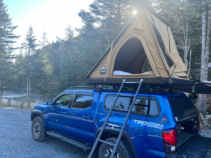 This blue Toyota Tacoma, equipped with a hard-shell rooftop tent, offers an adventurous rv rental alternative for overlanding.