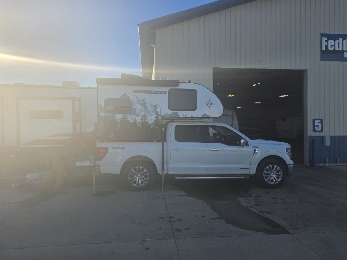 White pickup truck with a scenic truck camper