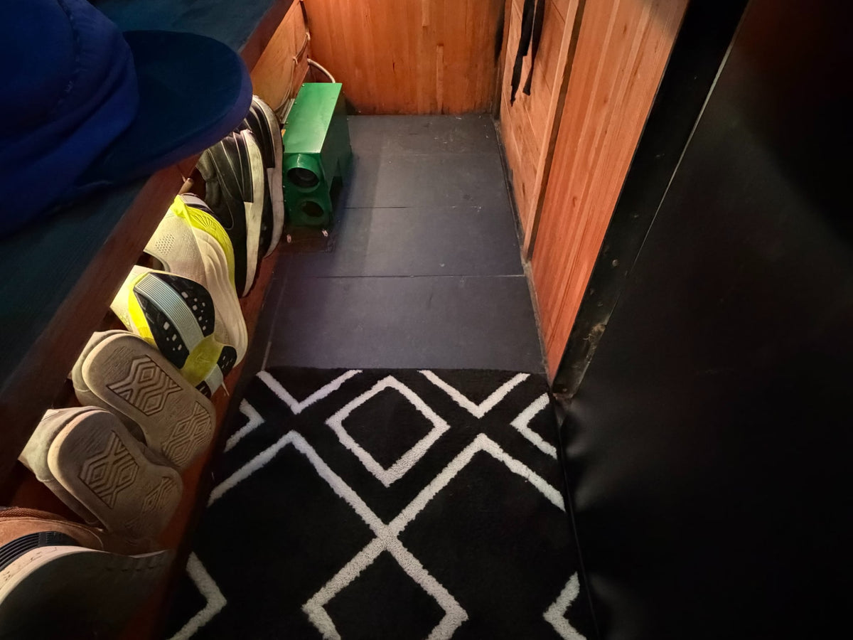 contrasting with the dark interior of an rv rental. Wooden ceiling visible above.|Inside an RV rental: narrow hallway with shoes under a bench — photo 3