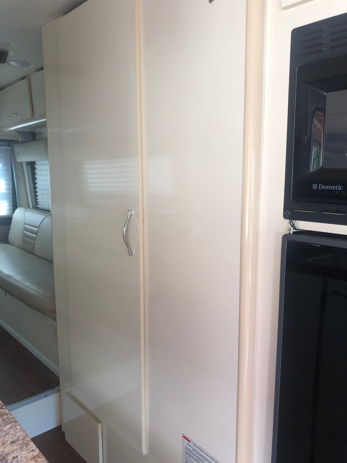 Inside an RV rental: view of a white storage cabinet, Dometic microwave, and cozy seating. Ready for your next travel adventure.