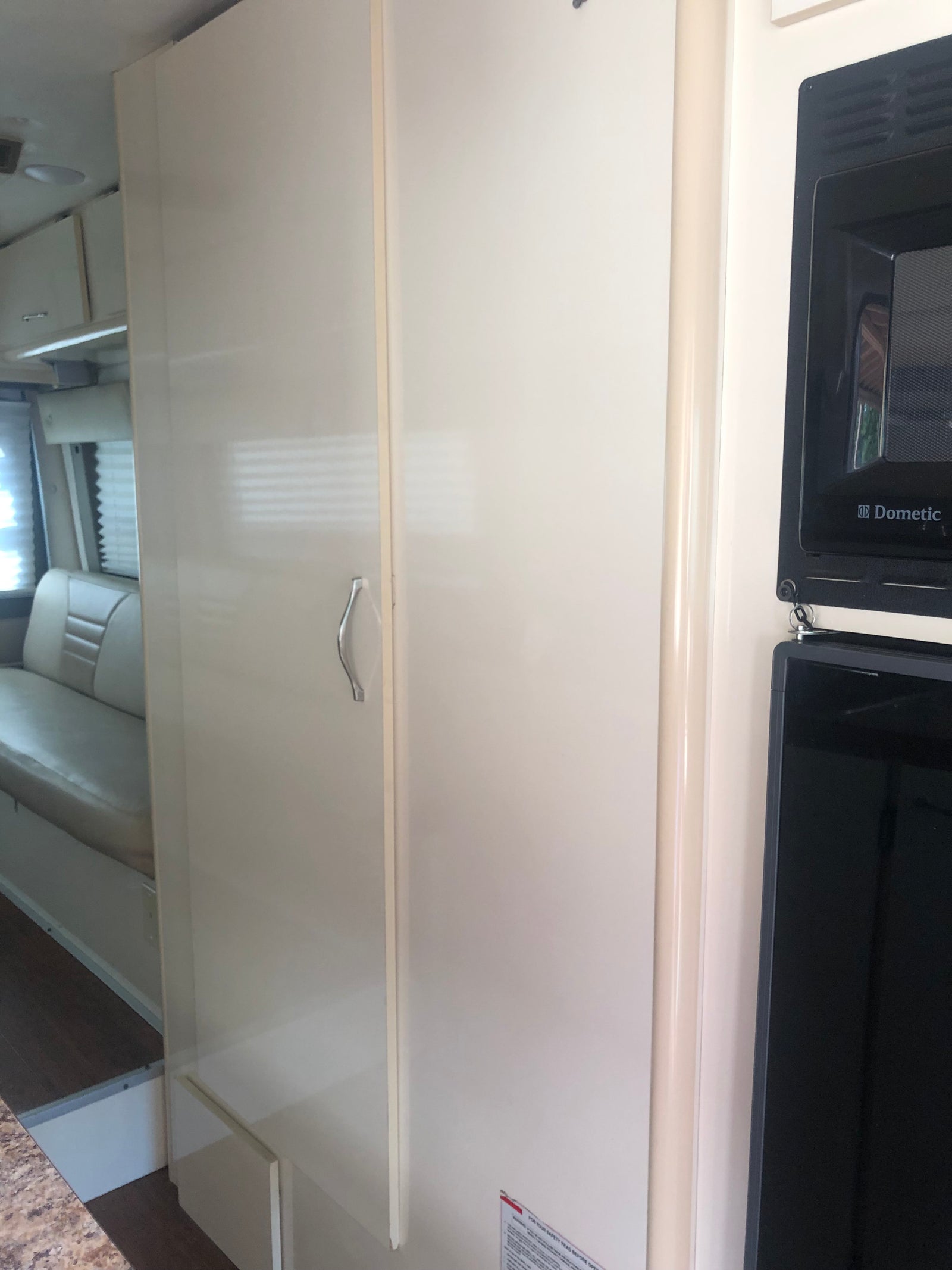 Inside an RV rental: view of a white storage cabinet, Dometic microwave, and cozy seating. Ready for your next travel adventure.