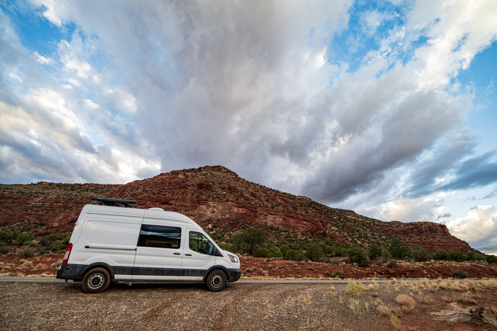 parked on a desert dirt path with mountains under a blue sky.|An RV rental van pauses at the entrance to Lake Mead National Recreation Area