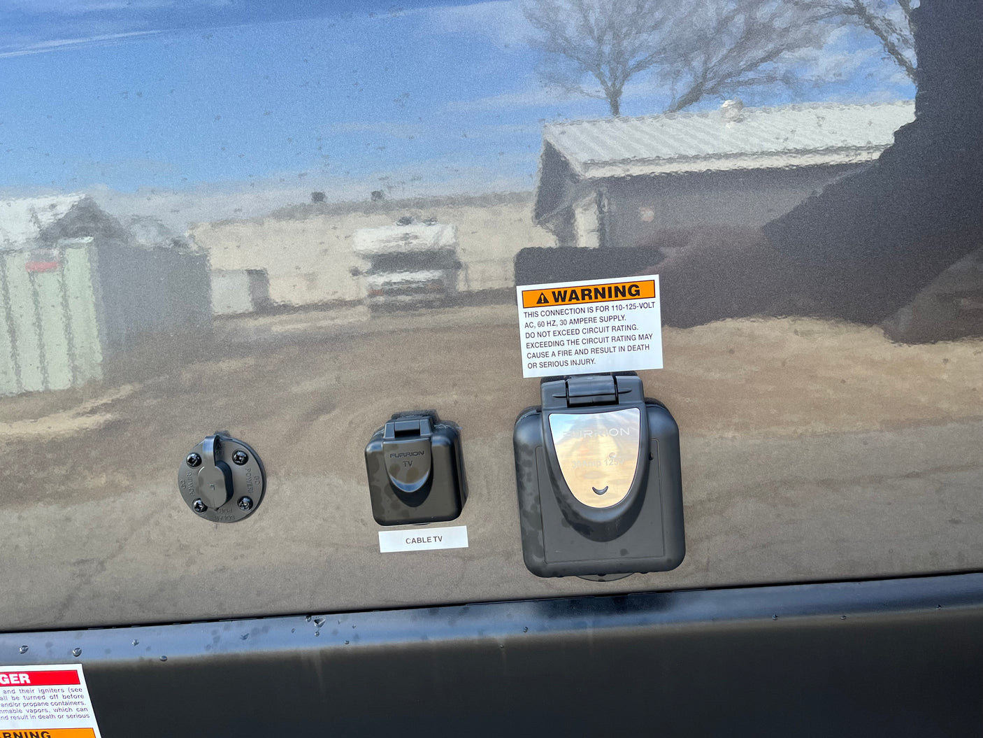 RV rental side panel with solar, cable TV, and 30-amp power connections. Clear warning labels visible.