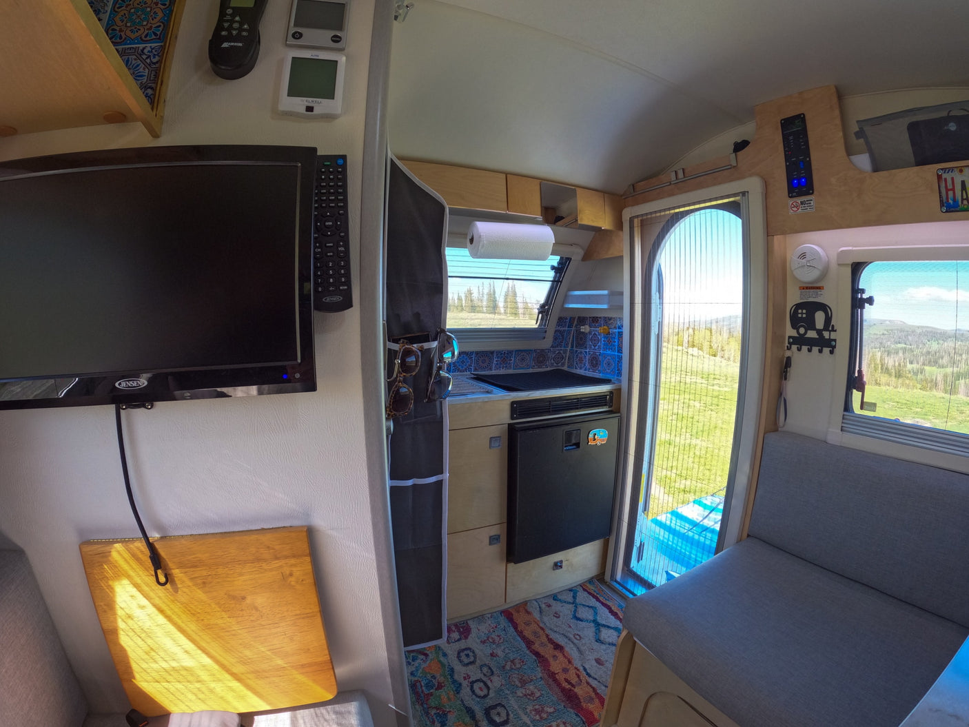 Explore this cozy RV rental interior with kitchen, TV, seating, and scenic window views. Ideal for travel.