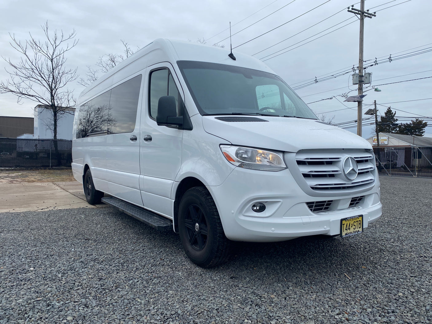 Modern white Mercedes-Benz Sprinter rv rental van with black wheels, parked on gravel in New Jersey, ready for adventure.