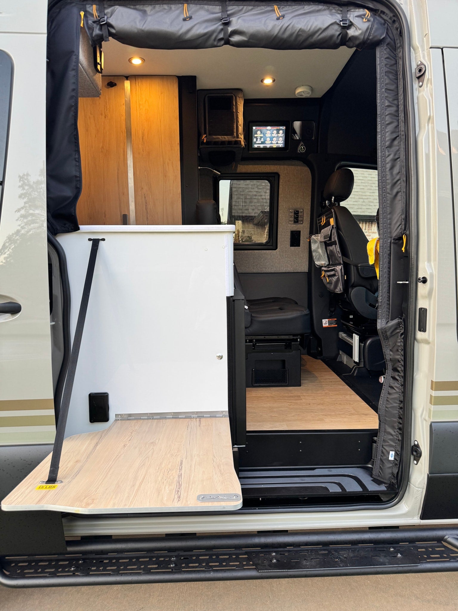Exploring an RV rental's accessible interior: an open side door showcases a handy fold-out table, comfy seating, and integrated tech.