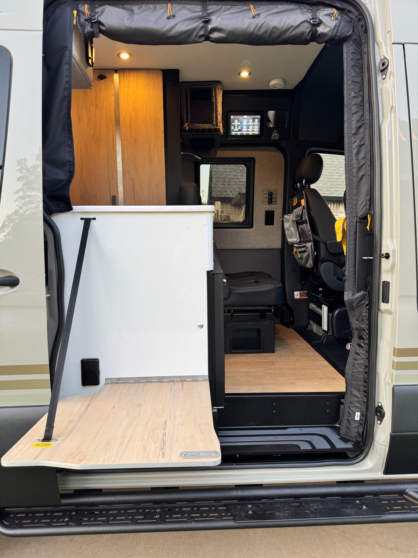 Exploring an RV rental's accessible interior: an open side door showcases a handy fold-out table, comfy seating, and integrated tech.