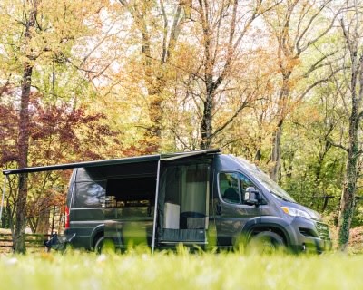 Modern dark grey camper van RV rental with an extended awning