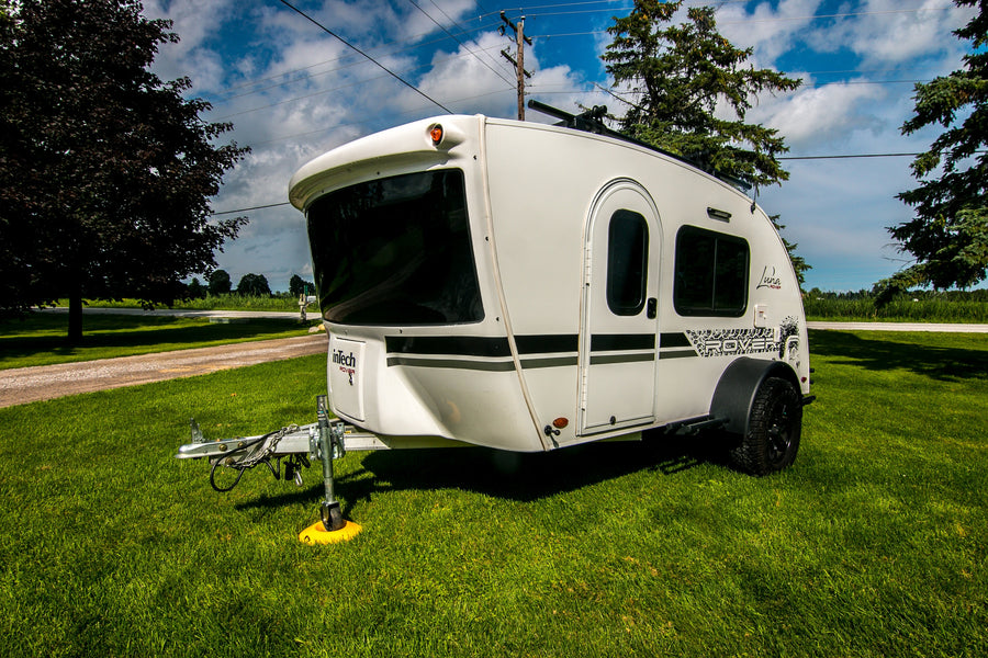 A modern white inTech Luna Rover compact travel trailer sits on green grass, ready for your next RV rental adventure.