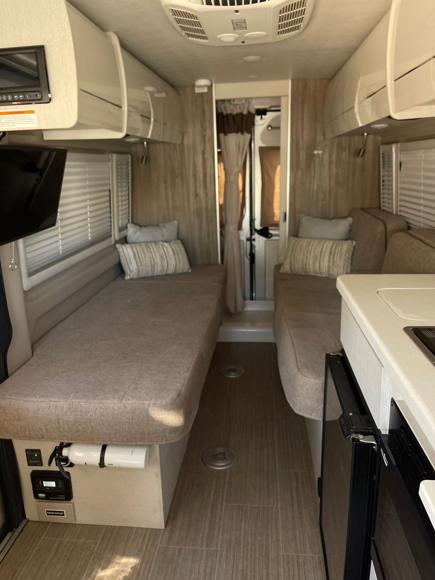 Spacious rv rental interior featuring convertible beds, compact kitchen, and overhead storage.