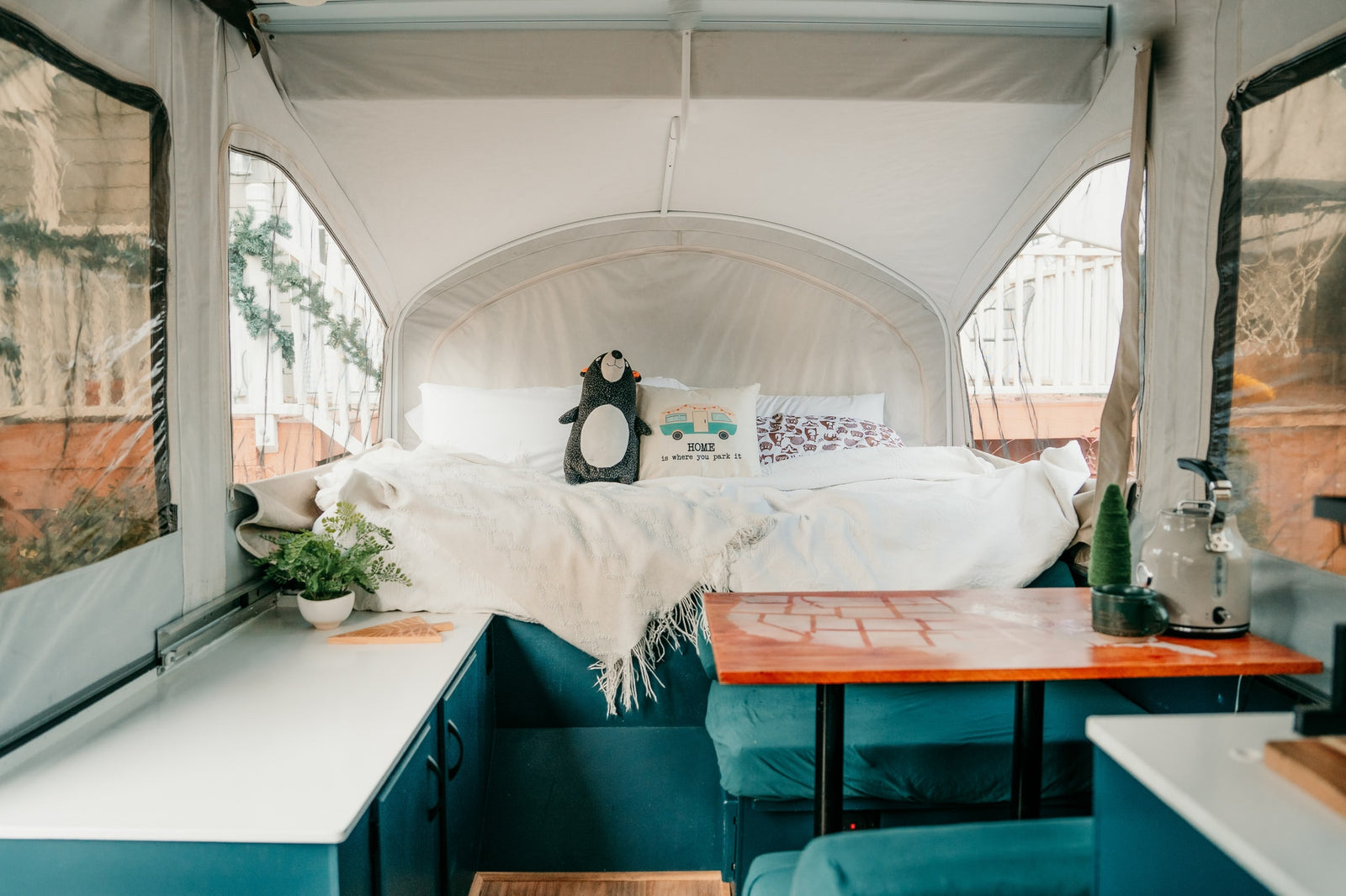 Cozy RV rental interior: comfy bed with plush toy, compact kitchen area, and clear scenic windows for travel.