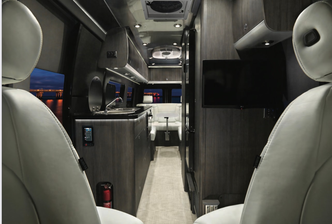 sleeps 2.|Experience van life! This RV rental offers peaceful nature retreats. Silver camper van in a grassy field