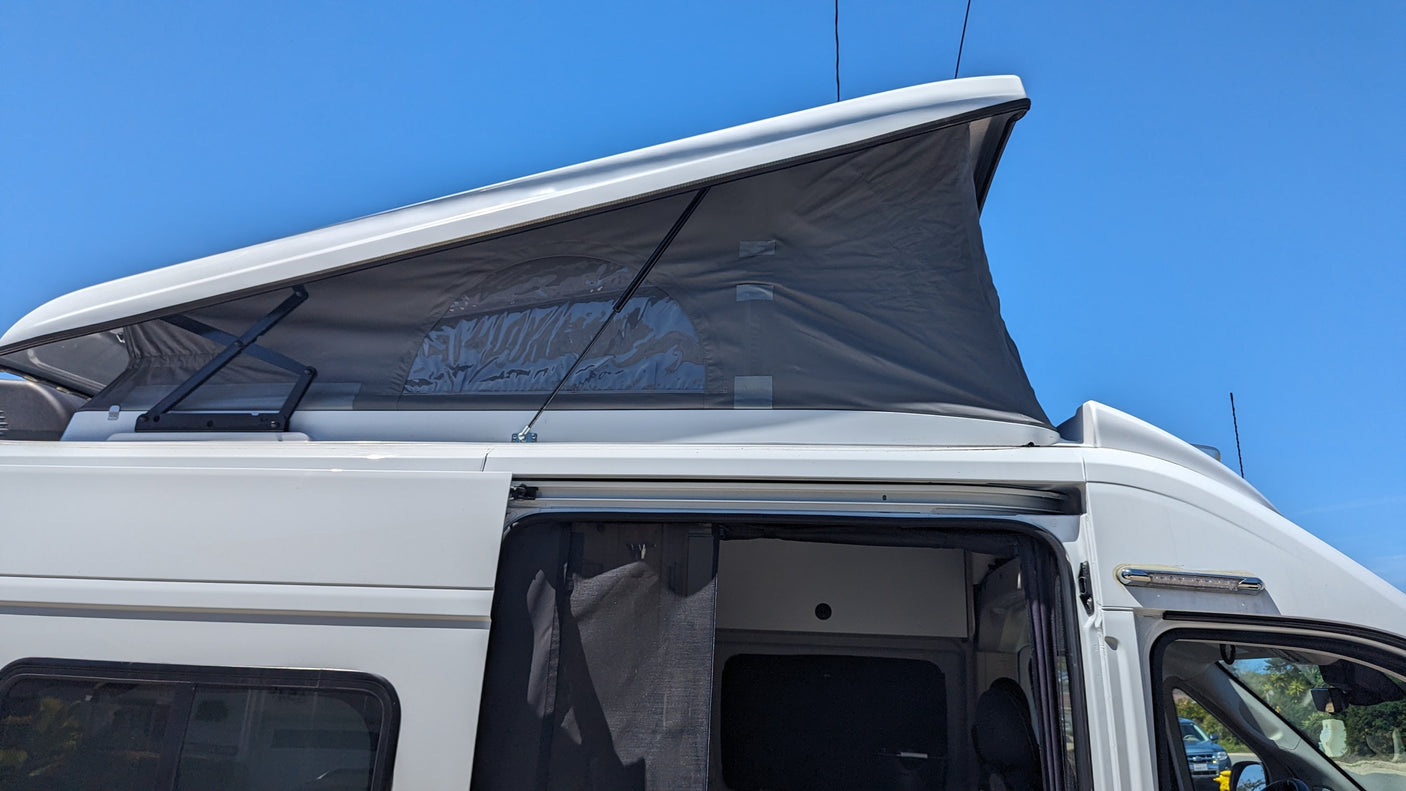 White RV rental camper van with an extended pop-top roof showing clear windows, and an open side door with a mesh screen.