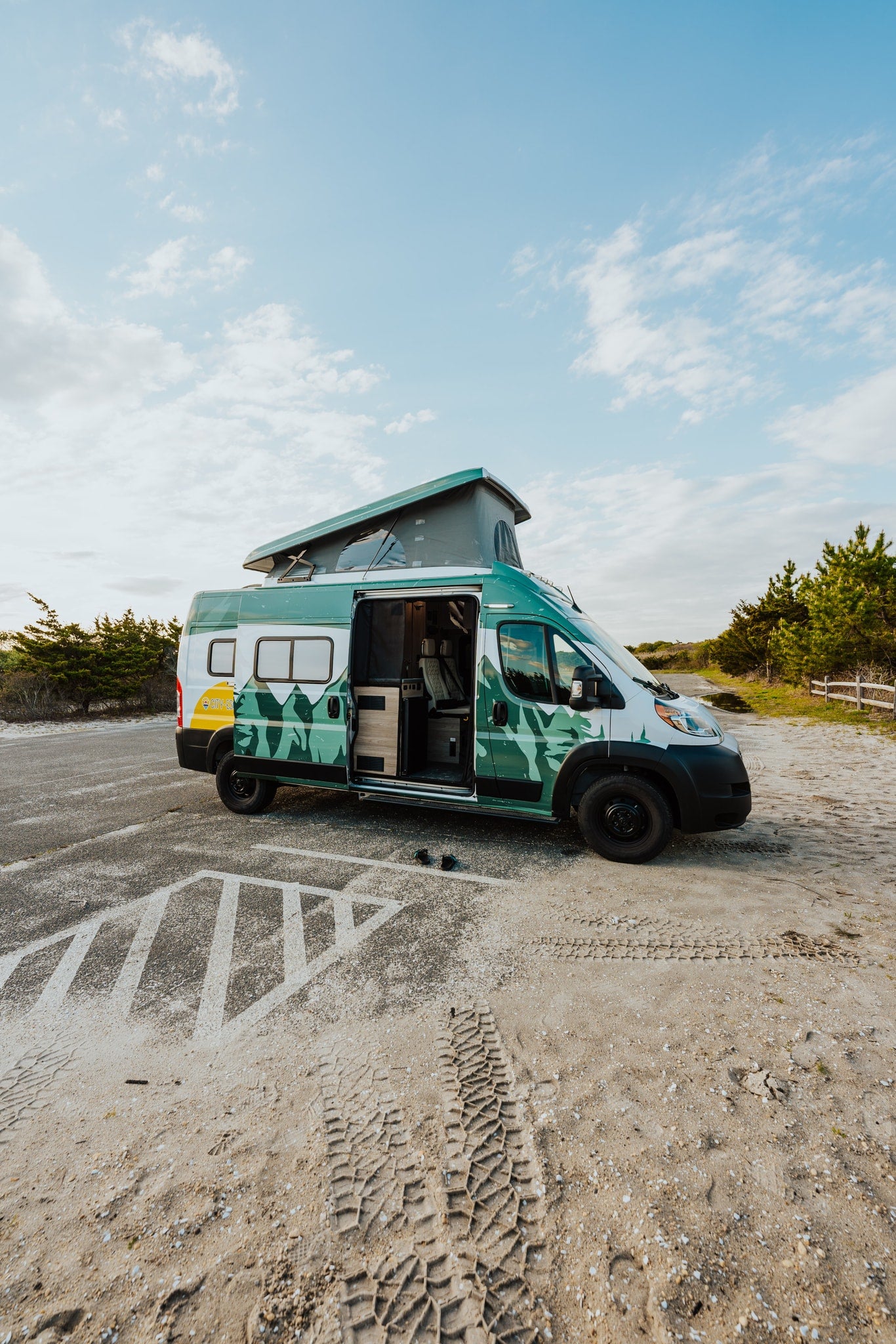 Vibrant green and white RV rental camper van with a pop-top roof and open door