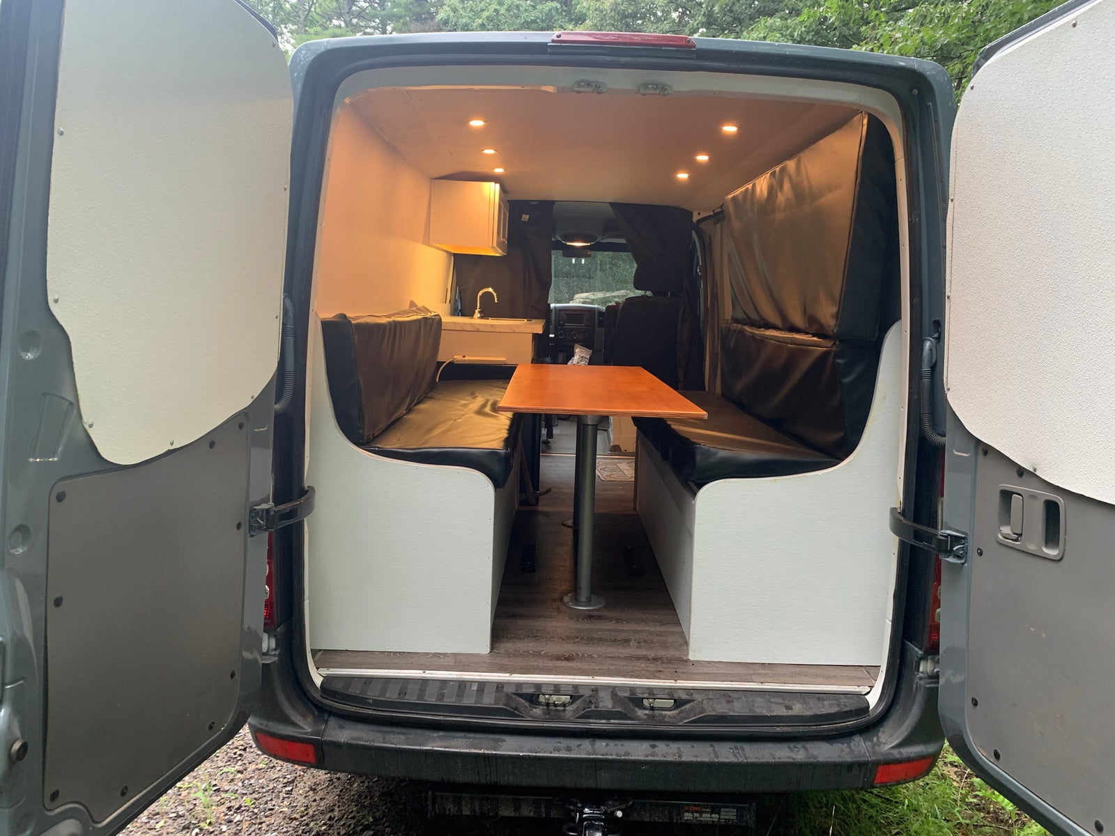 Explore this RV rental's cozy camper interior: dining area, sink, and warm lighting for your mobile adventures.