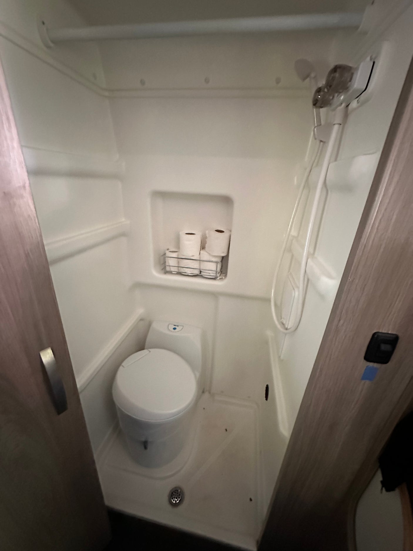 This compact wet bath in an RV rental features a toilet, shower, and convenient toilet paper storage.
