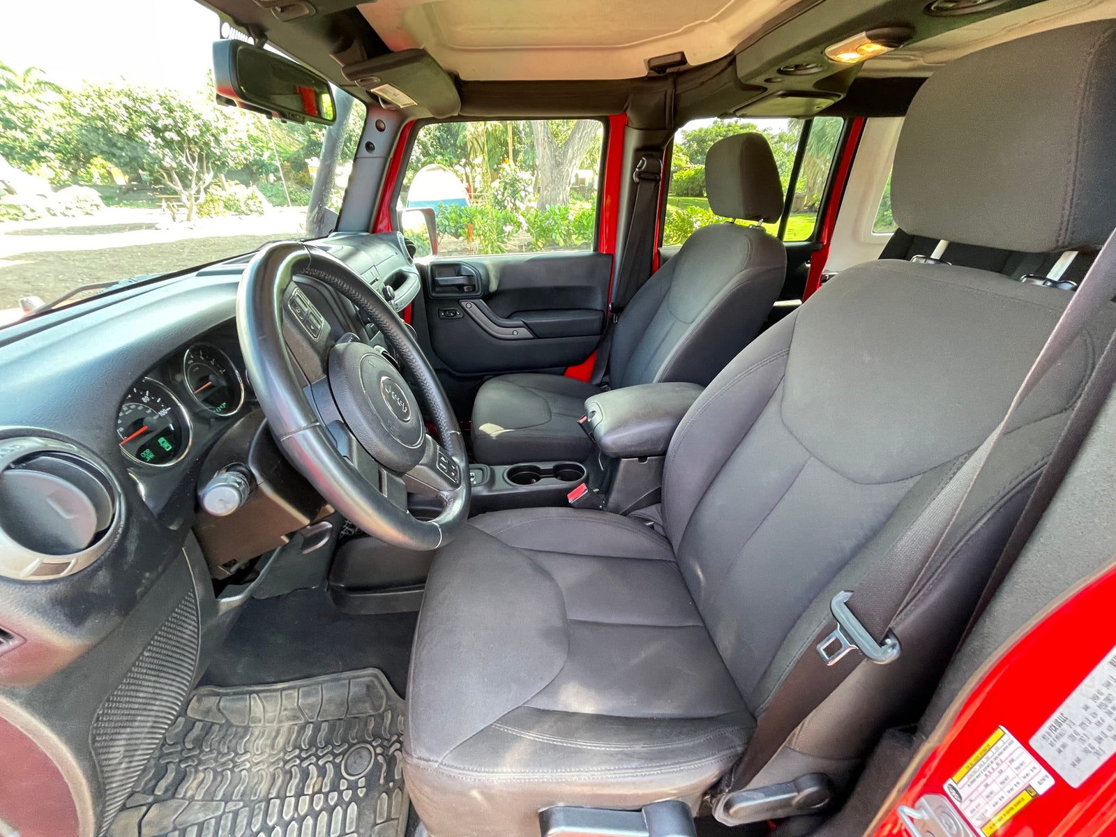 Spacious red Jeep Wrangler interior, showing front cabin, steering wheel, and gray seats. Perfect for your next RV rental adventure.