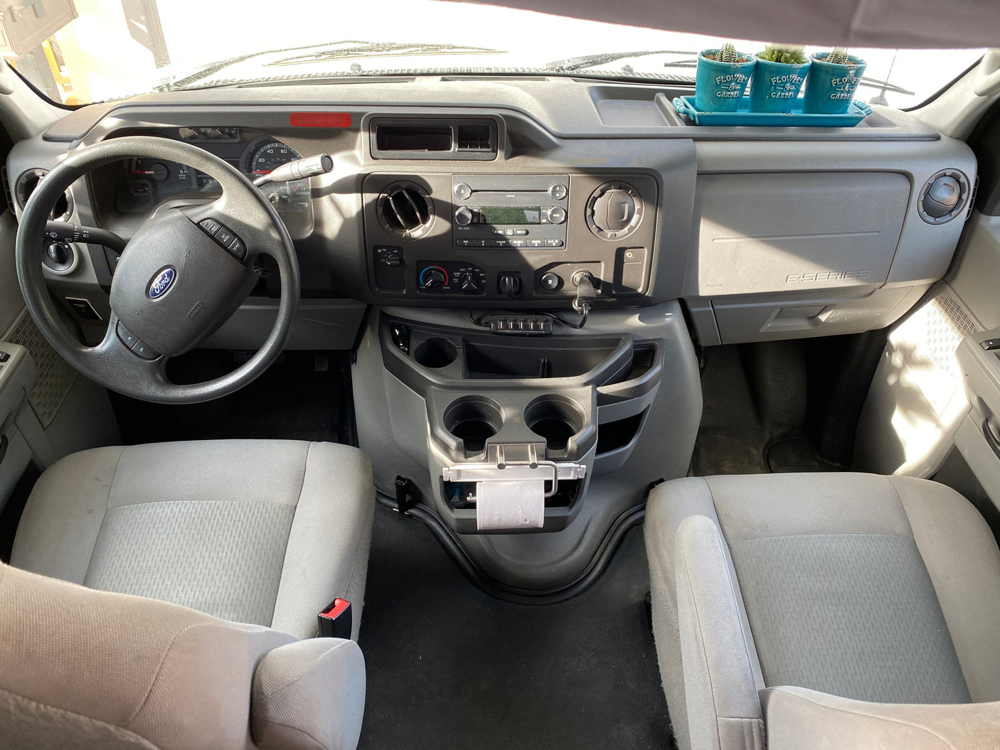 Spacious Ford E-Series RV rental interior, featuring dashboard, steering wheel, and a charming succulent plant display.