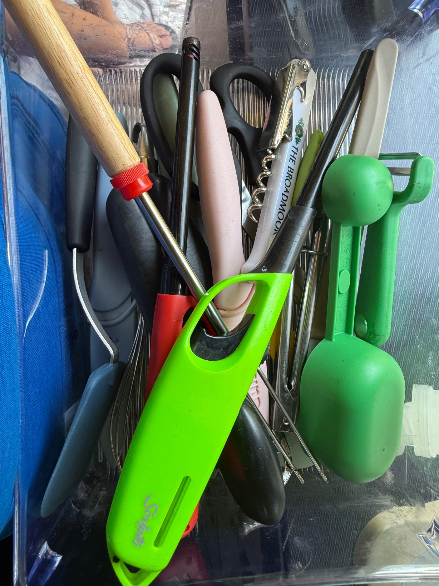 RV rental kitchen tools: long lighters, a peeler, scissors, corkscrew, and other cooking utensils in a clear container.
