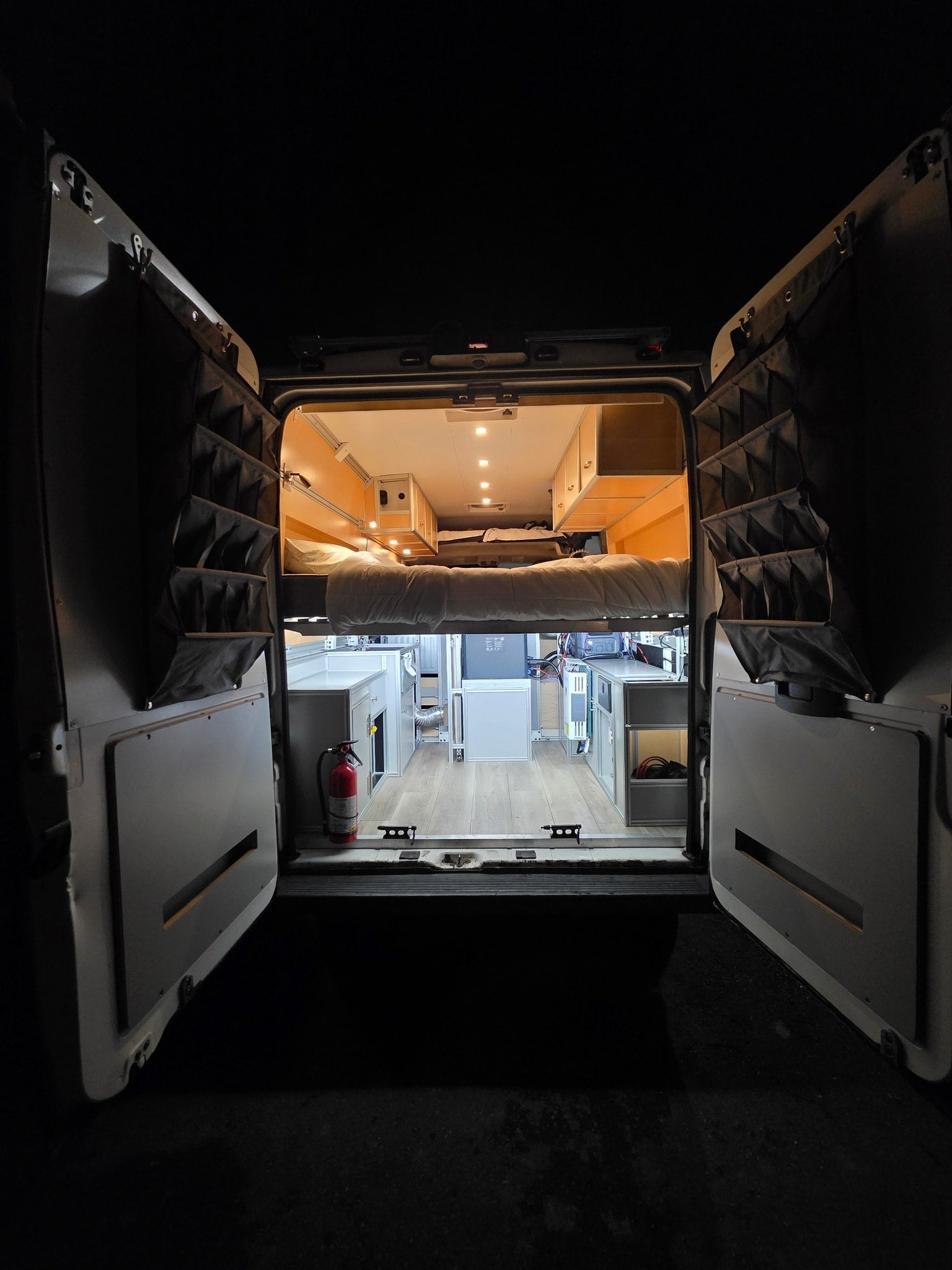 Step into this bright rv rental camper van, revealing a raised bed, cabinetry, and door organizers, perfect for mobile adventures.
