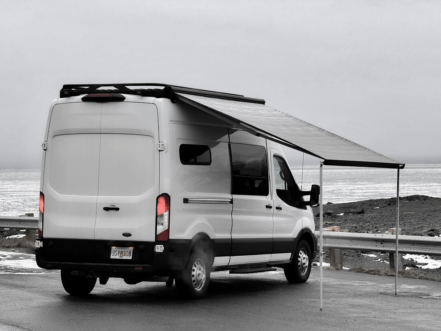 parked by snowy mountains.|White Ford Transit RV rental camper van with roof lights