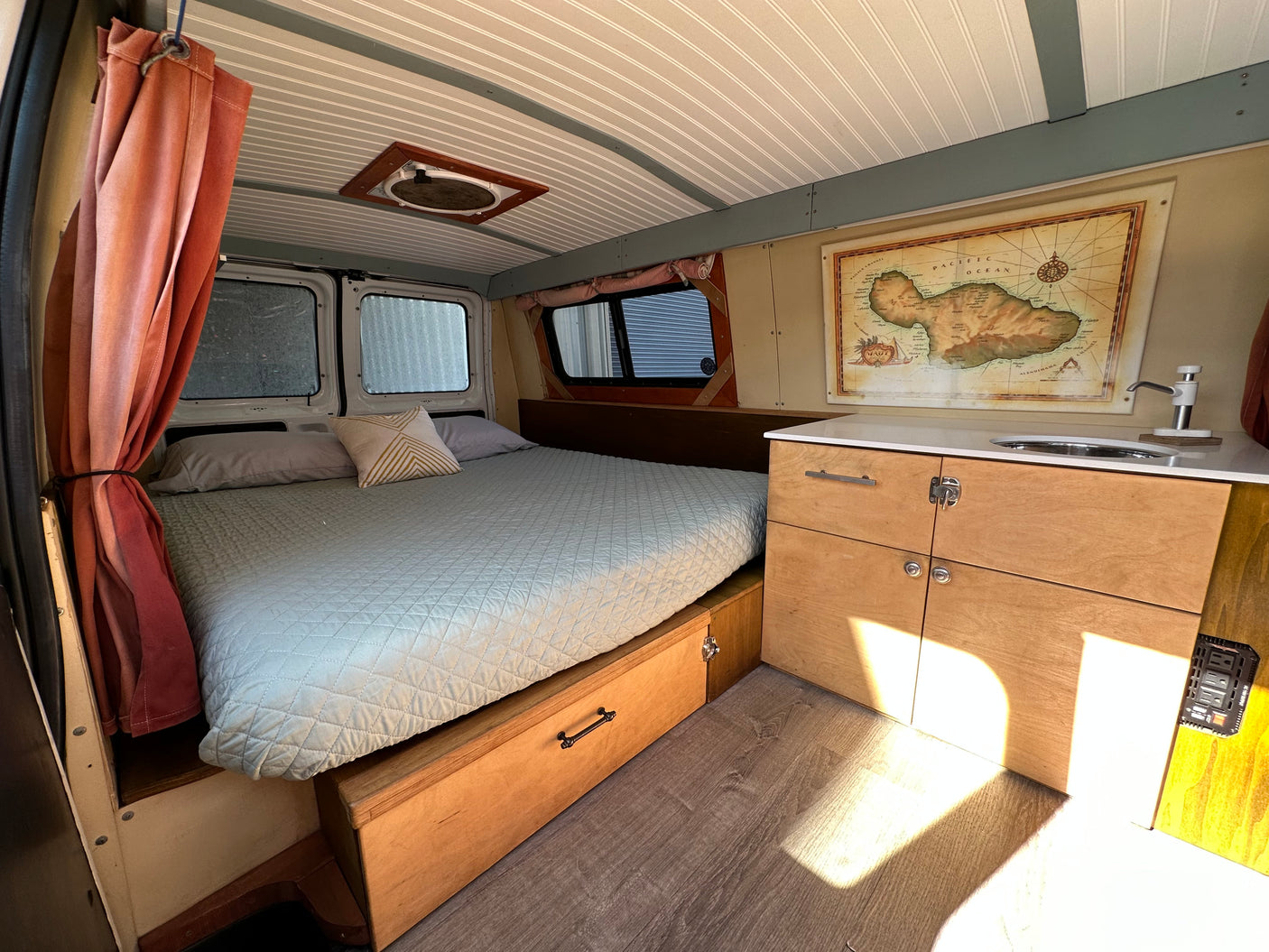 Cozy RV rental interior featuring a comfortable bed, functional kitchen with sink, and smart storage solutions for travel.