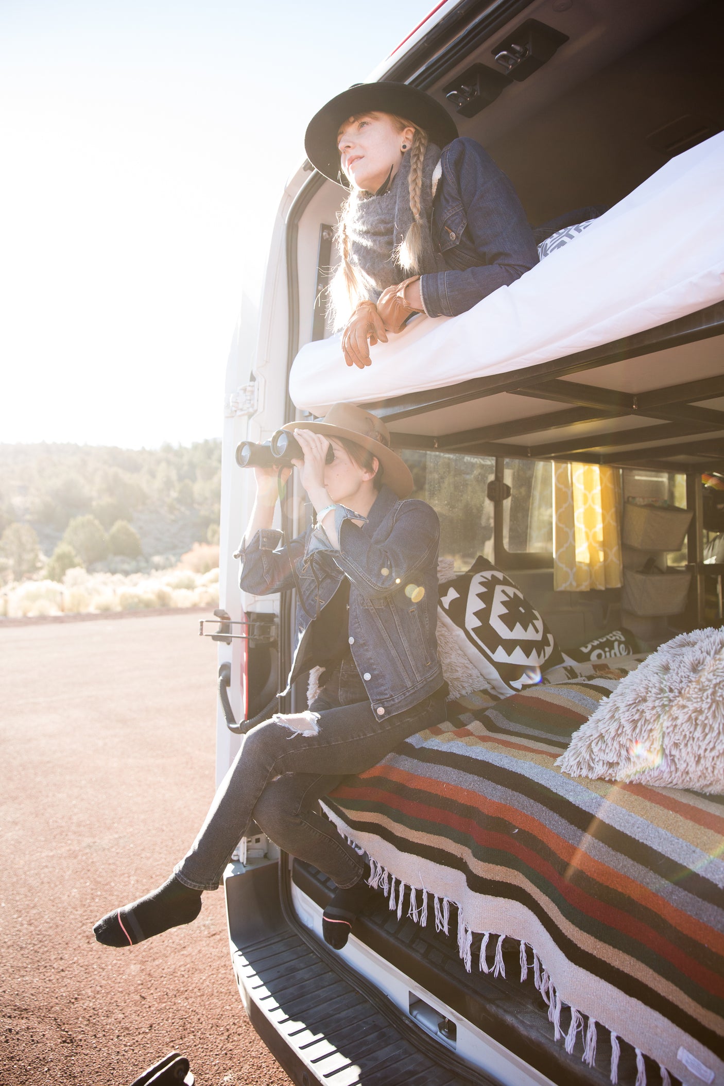 RV rental adventure: Two women in their camper van, one on the upper bunk, one with binoculars below.