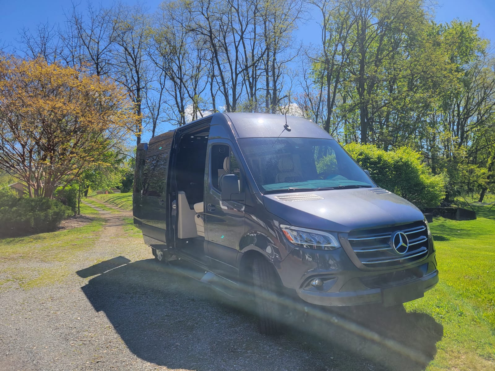 and plush seats.|Dark gray Mercedes Sprinter van on a gravel driveway