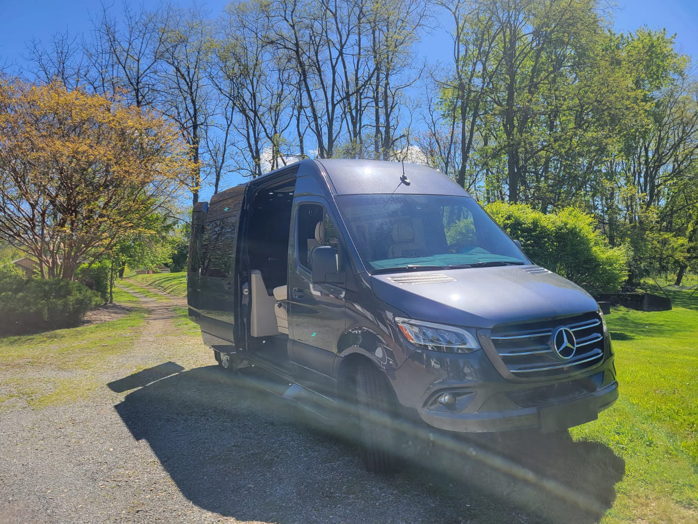 and plush seats.|Dark gray Mercedes Sprinter van on a gravel driveway