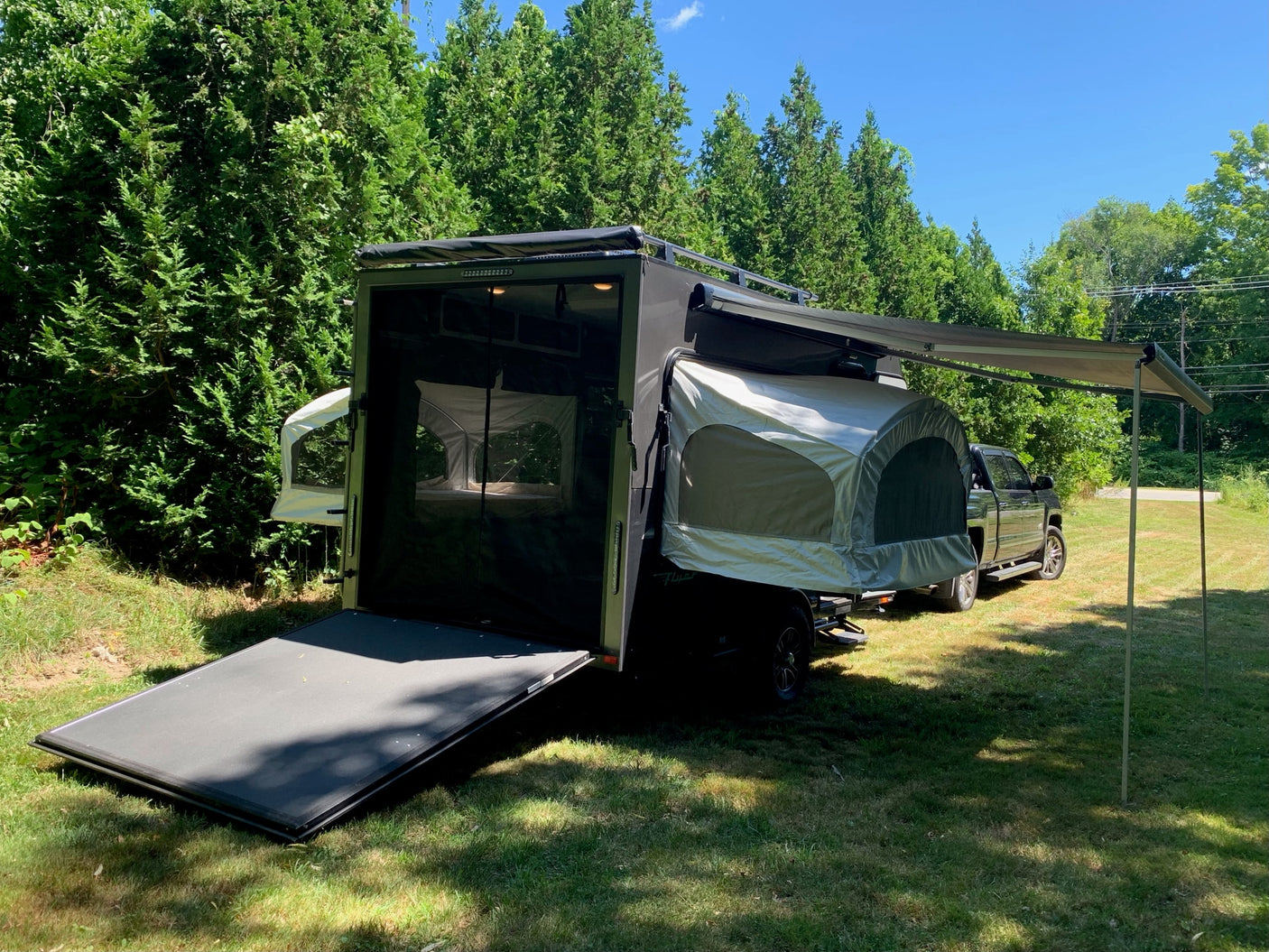 This dark gray RV rental trailer with pop-out tents and an awning offers outdoor camping adventure, ready for your next trip.