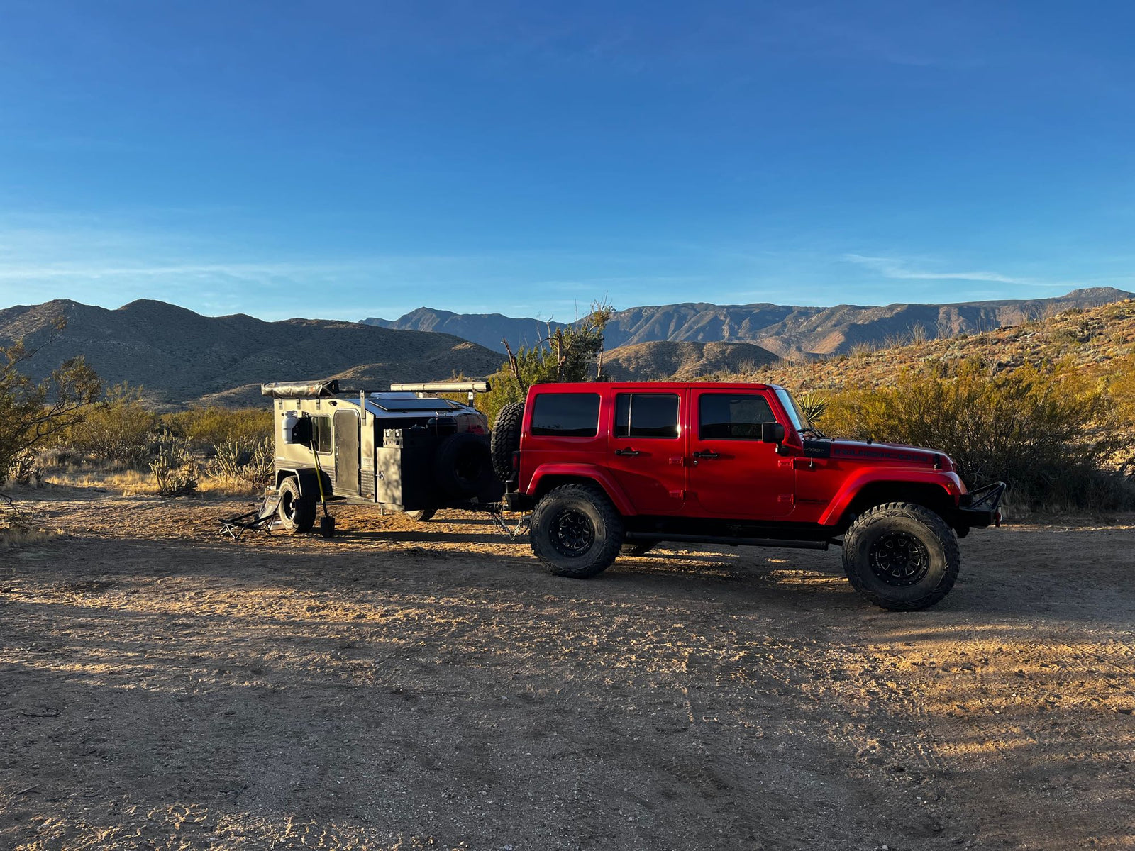 ready for winter camping adventures in rugged landscapes.|An adventurous RV rental setup: a red Jeep and an off-road trailer parked for desert camping at dusk. Perfect for exploration.|Breathtaking desert mountains with rugged peaks and sparse flora. An RV rental offers exploration of this vast