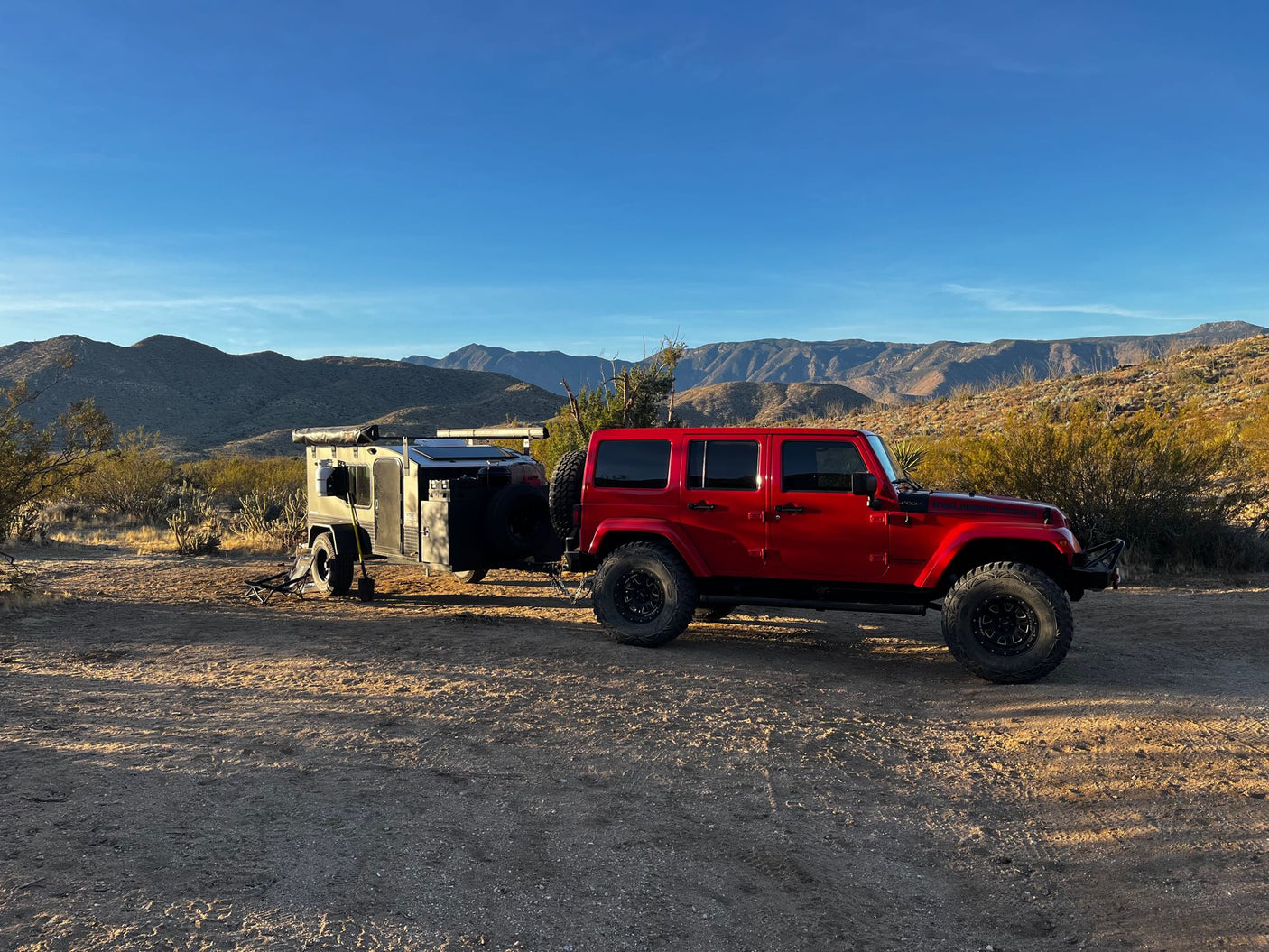 ready for winter camping adventures in rugged landscapes.|An adventurous RV rental setup: a red Jeep and an off-road trailer parked for desert camping at dusk. Perfect for exploration.|Breathtaking desert mountains with rugged peaks and sparse flora. An RV rental offers exploration of this vast