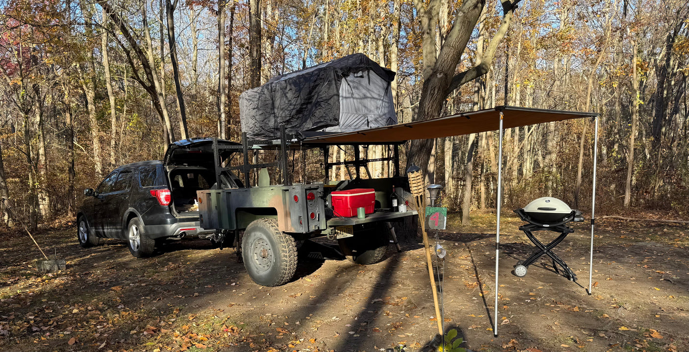 Overlanding setup with SUV, trailer, rooftop tent & awning. Great for an RV rental adventure in the woods.